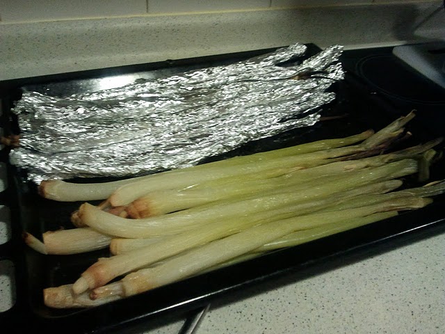 Calçots tot just sortits del forn, treient-los l'embolcall d'alumini