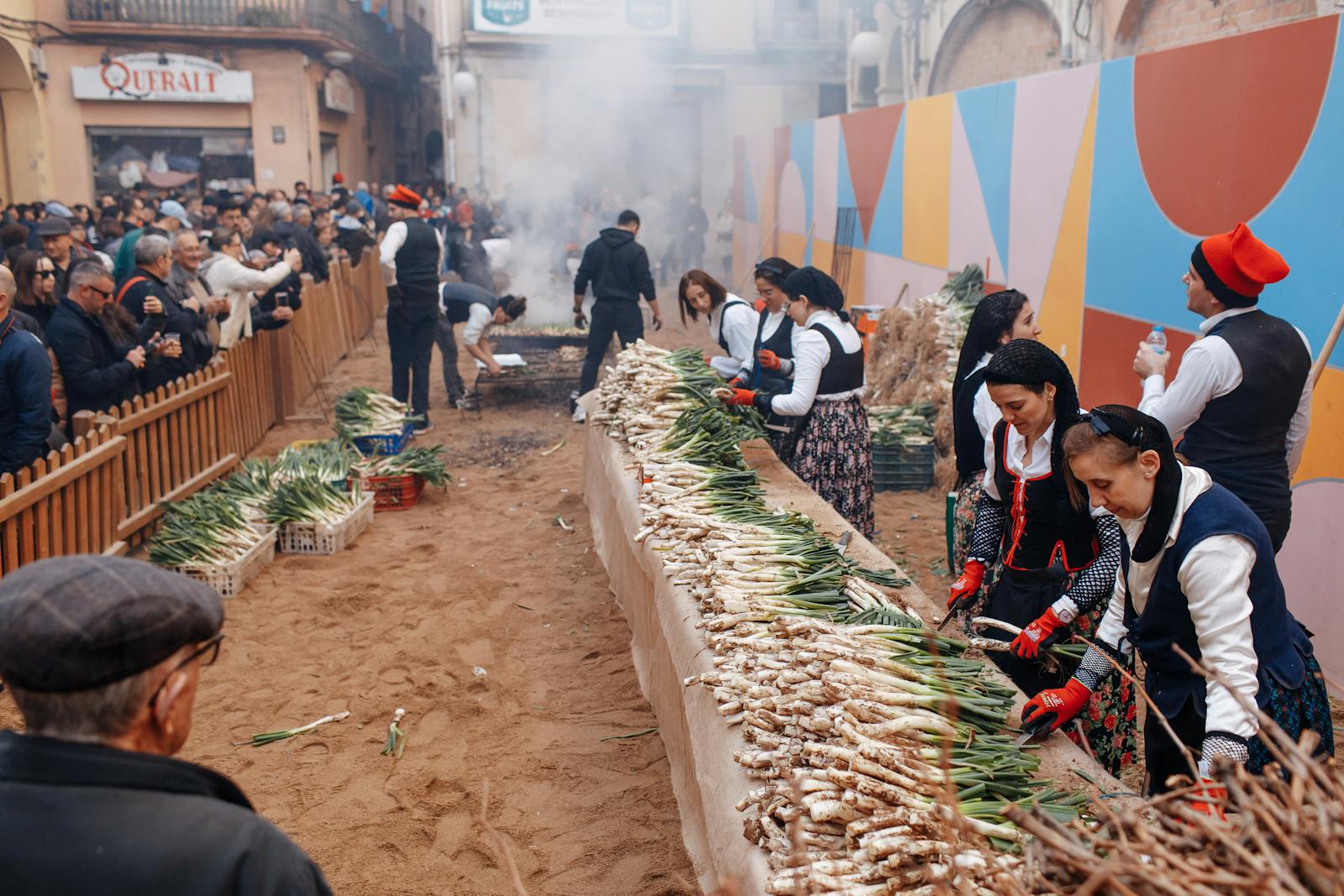Gent amb roba tradicional al voltant d'una taula a una calcotada